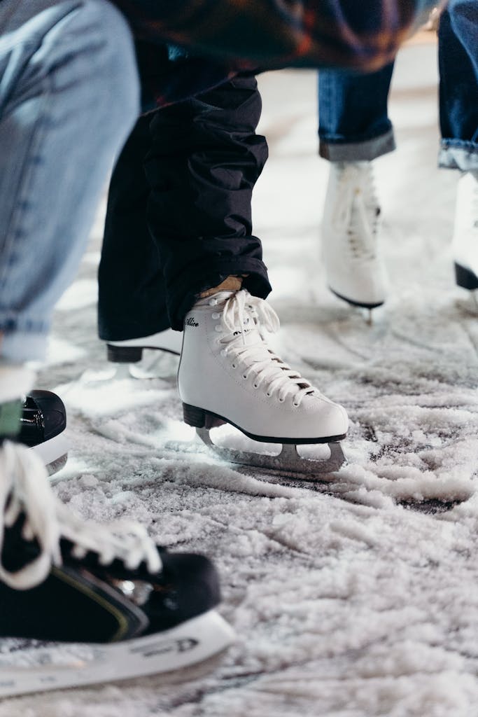 Close-up view of people wearing ice skates on a snowy outdoor surface, ready for ice skating.